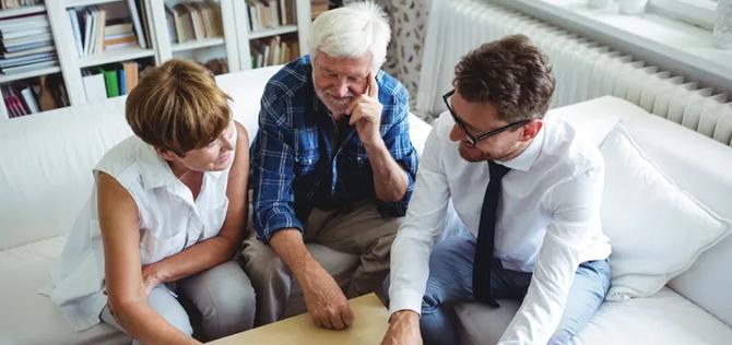 Older couple meeting with an advisor in their livingroom. 