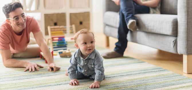 Caucasian gay fathers and baby relaxing in living room