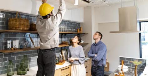 Couple watching a construction worker fix the ceiling in their kitchen