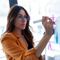 Business young woman working on white board with post it stickers in the office.