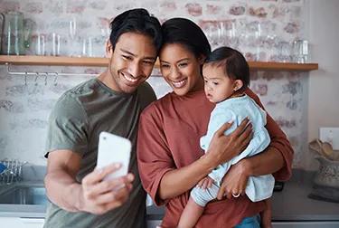 Happy, parents and baby with down syndrome taking selfie together in kitchen of family home. Happiness, smile and mother and father bonding with disabled child while taking picture on phone in house