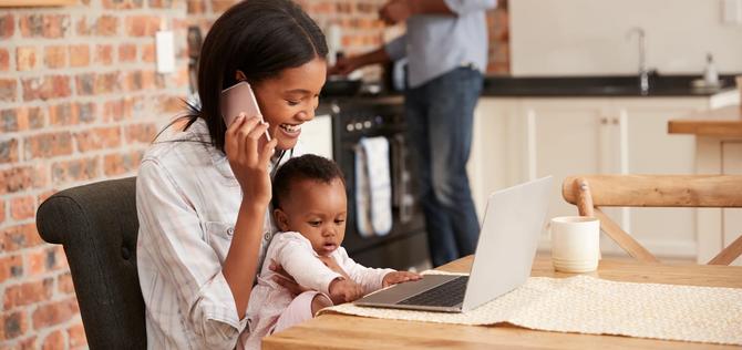 Mother And Baby Daughter Use Laptop As Father Prepares Meal; Shutterstock ID 627678074; PO: redownload; Job: redownload; Client: redownload; Other: redownload