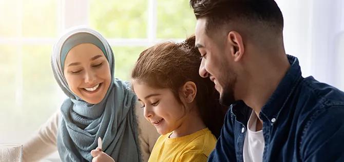 Cheerful young family of three sitting at table, eating delicious meal And chatting