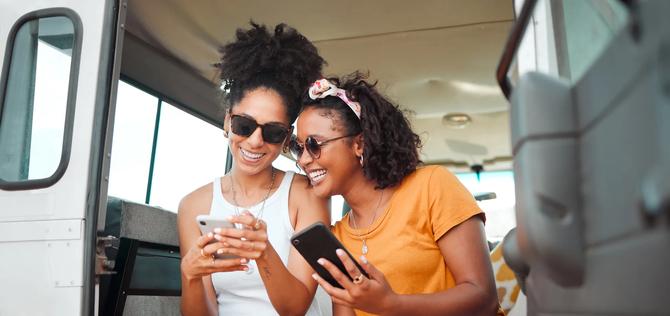 Black friends, phone and social media travel in communication together for road trip adventure. Happy and excited African American women sharing moments of traveling on mobile smartphone for vacation.