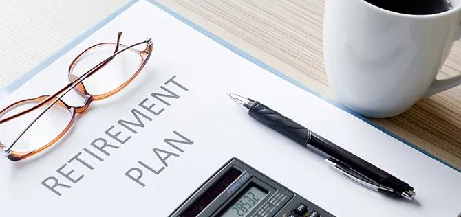 Calculator, glasses and pen on a retirement plan binder