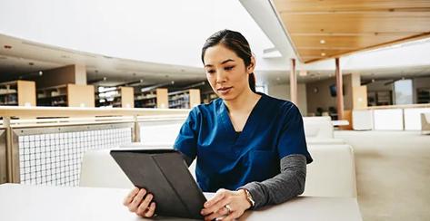 Female medical student using digital tablet at table in library