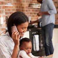 Mother And Baby Daughter Use Laptop As Father Prepares Meal; Shutterstock ID 627678074; PO: redownload; Job: redownload; Client: redownload; Other: redownload