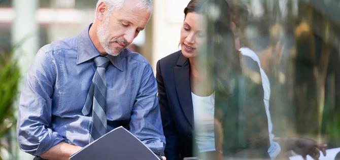 a man and woman sit outside and discuss business