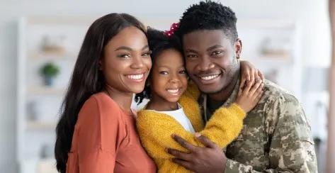Man In camouflage uniform smiling and embracing with spouse and child