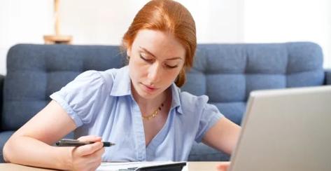 A woman is sitting at a table reviewing her finances.