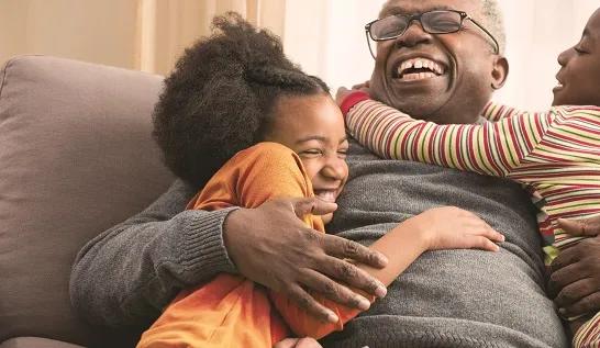 Older man hugging grandchildren on sofa
