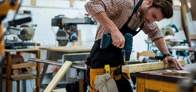 Young male woodworker using a drill