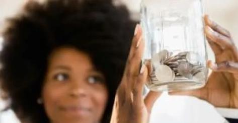Young lady holder a jar full of coins and looking pleased 