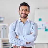 Smile, education and portrait of man teacher in a classroom or school and happy to study in a college or university. Academy, educator and young person or worker arms crossed and confident in class.