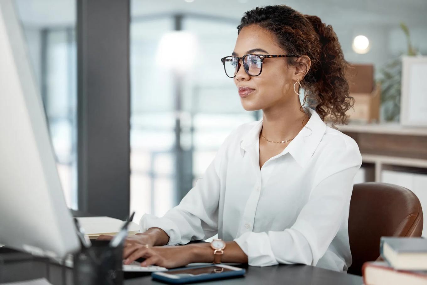 Professional woman at desk, working at computer with email and writing article at digital marketing agency. Focus, web design and typing at desktop PC with female copywriter, notes and SEO content.