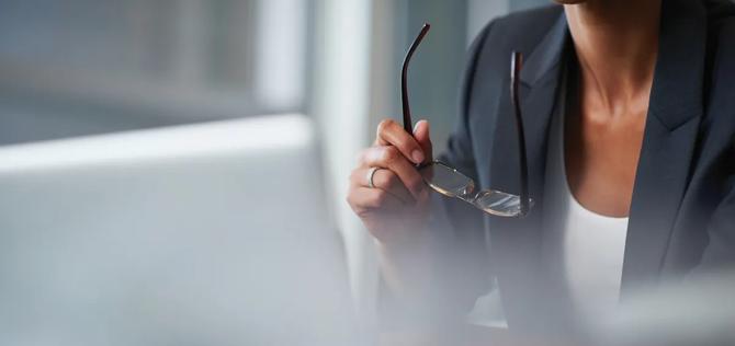 business woman holds her spectacles during a meeting