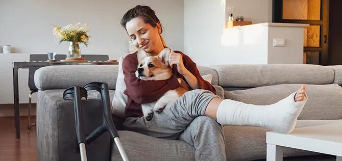 Woman on couch at home with crutches and leg cast