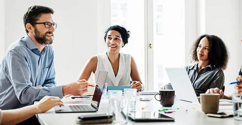 A male addresses a group of fellow colleagues during a meeting in a workplace conference room