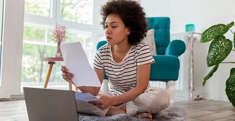 Beautiful woman sitting on the living room floor, calculating bank loan payout rates and paying household bills