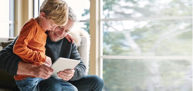 Adult male with child sitting on his lap using handheld computer 