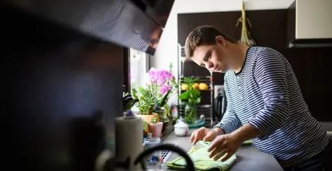 Young adult man with Down syndrome helping in the kitchen