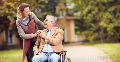 senior man in wheelchair with happy caregiver daughter.