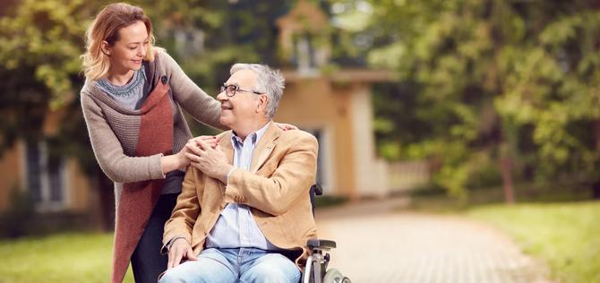 senior man in wheelchair with happy caregiver daughter.