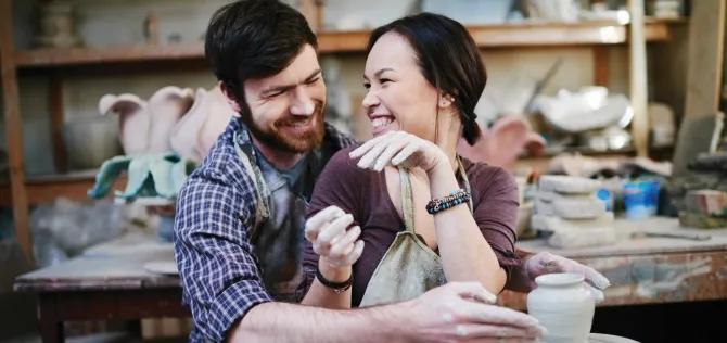 Happy couple making a ceramic vase together. 