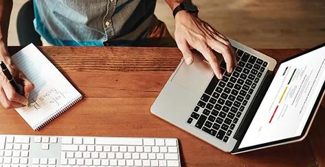 A man using one hand to navigate the Voya Behavioral Finance website on a laptop keyboard