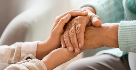 Adult daughter holding hands with mother.