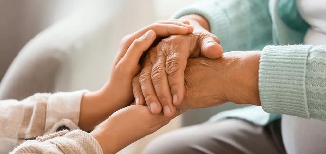 Adult daughter holding hands with mother.