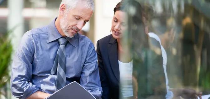 a man and woman sit outside and discuss business