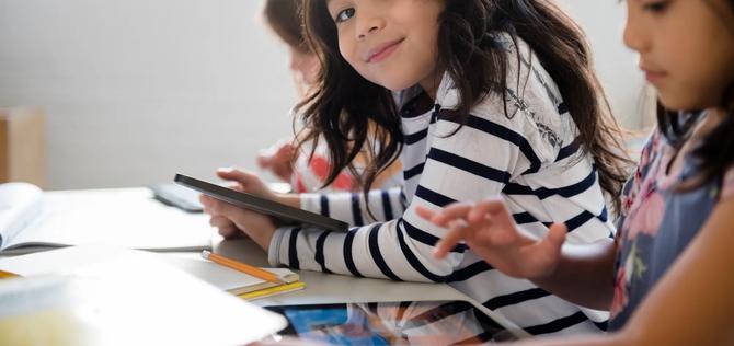 Portrait of smiling girl using digital tablet in classroom