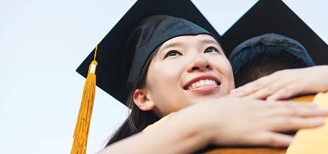 young university graduate hugging her classmate