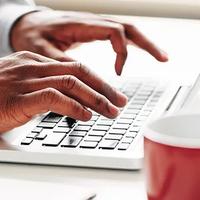 A man's hands typing on a laptop keyboard to enter information into myOrangeMoney
