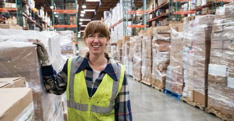 Portrait of single female caucasion worker wearing safety vest in a distribution warehouse.