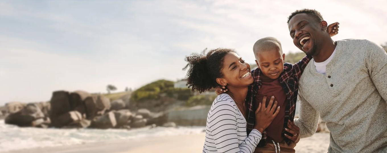 Smiling young man and woman with their son on the beach. Beautiful family on vacation at beach.
