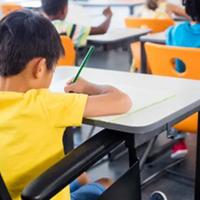 Boy using wheelchair writing at school desk