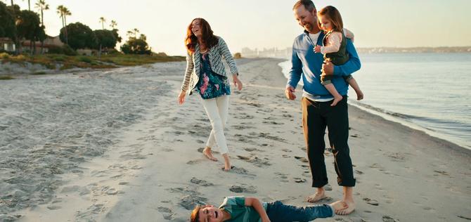 Family of four walking and paying along beach 