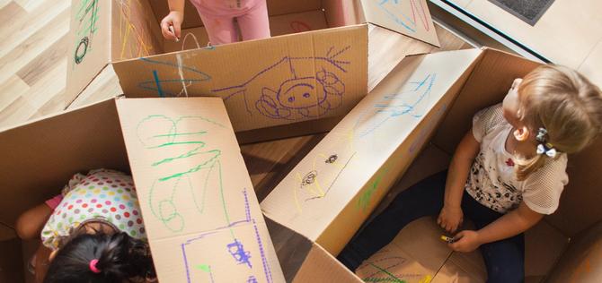 Several kids playing in boxes with crayons 
