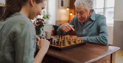 Senior man playing chess with his caregiver.