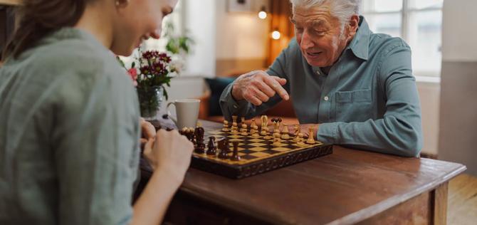 Senior man playing chess with his caregiver.