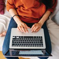 Overhead close up of a young woman working on laptop