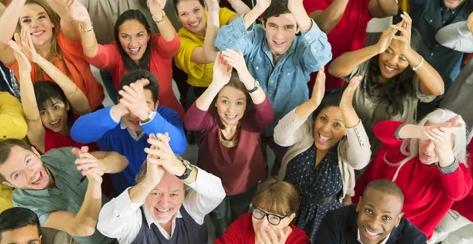 Diverse group of people looking upward and clapping their hands