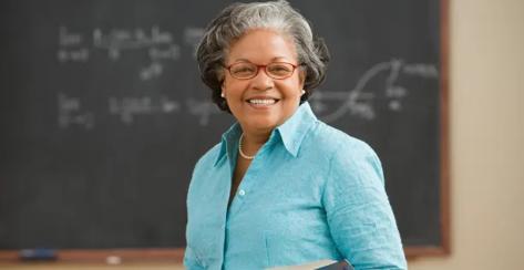 Lady smiling while standing in front of a chalkboard.