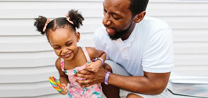 Father holding young daughter who is laughing.