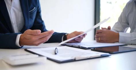 Two employees sitting together at a table reviewing benefits together,