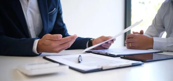 Two employees sitting together at a table reviewing benefits together,