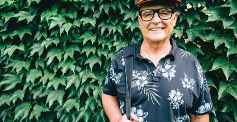 Smiling senior man standing in front of hedges