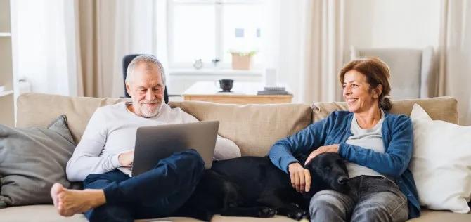 A couple sitting on their couch reading an article in Voya's Financial Wellness library.